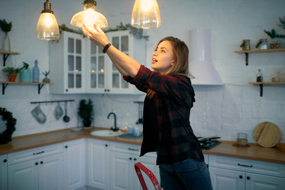 Lady changing light bulbs - 5 Tips for Apartment Renters to Save Energy
