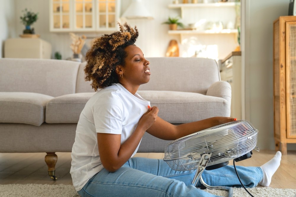 Girl with fan in apartment - How to Cool Down Your Apartment This Summer