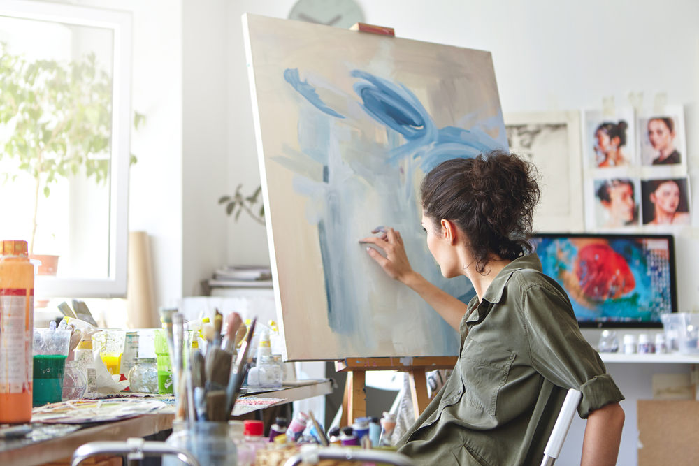 Woman in apartment enjoying her hobby of painting